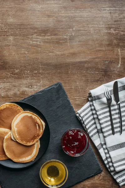 Top view of tasty pancakes with maple syrup and jam on wooden table — Stock Photo