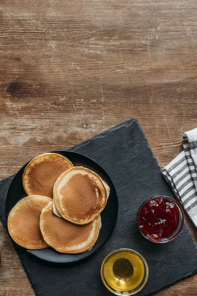 Top view of delicious pancakes with maple syrup and jam on wooden table — Stock Photo