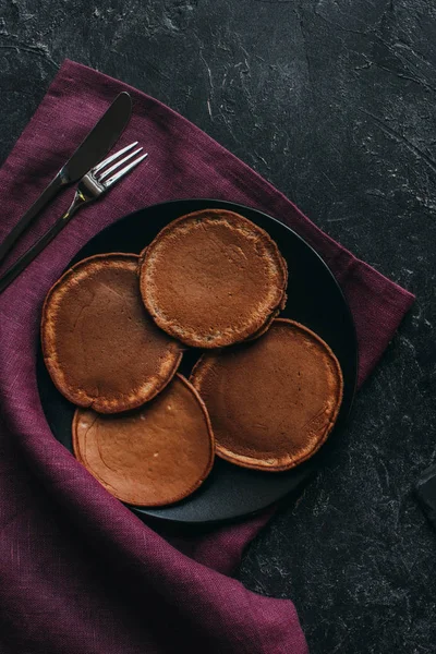 Teller mit Schokolade-Pfannkuchen mit Besteck auf roter Serviette — Stockfoto