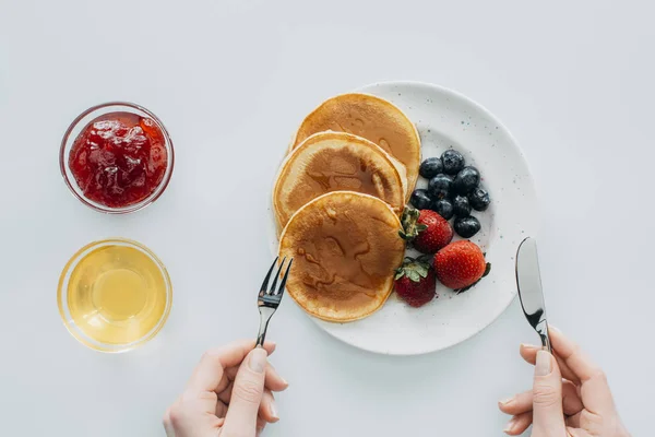 Plan recadré de femme mangeant des crêpes avec des baies sur la table blanche — Photo de stock