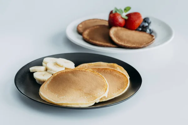 Close-up shot of plates of tasty pancakes with fruits on white table — Stock Photo