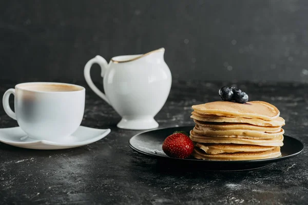 Plato de deliciosos panqueques apilados con taza de café — Stock Photo
