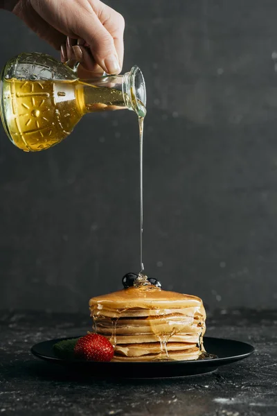 Plan recadré d'une femme versant du sirop d'érable sur une pile de crêpes fraîchement cuites — Photo de stock