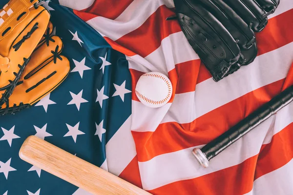 Vista superior de pelota de béisbol, murciélagos y guantes en la bandera americana - foto de stock