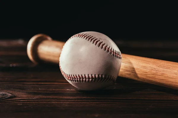 Vue rapprochée de la balle de baseball en cuir blanc et de la batte sur une table en bois — Photo de stock