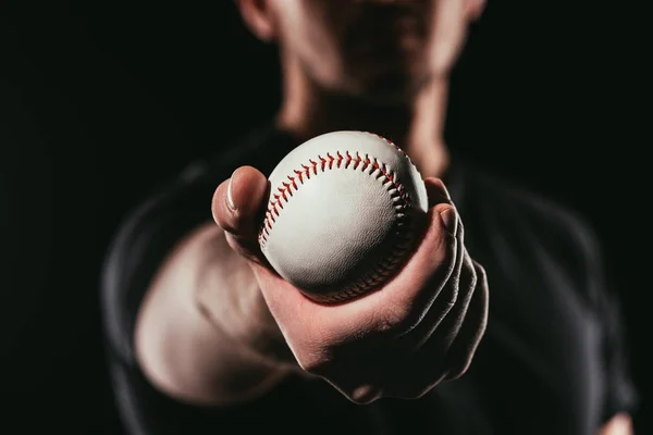 Enfoque selectivo del hombre sosteniendo pelota de béisbol aislado en negro - foto de stock