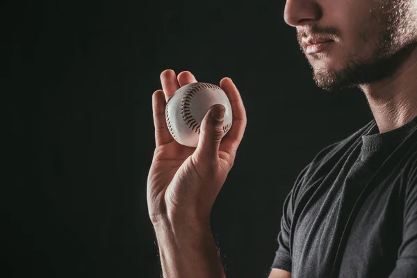 Cropped shot of young bearded sportsman holding baseball ball isolated on black — Stock Photo