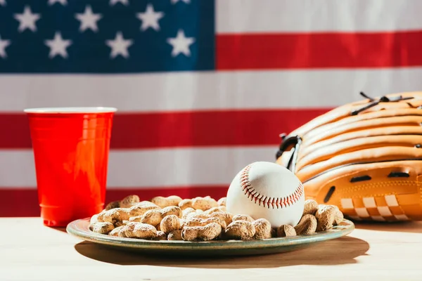 Close-up view of baseball ball and glove, peanuts and red plastic cup — Stock Photo