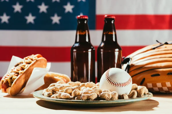 Vista de cerca de la pelota de béisbol en el plato con cacahuetes y botellas de cerveza - foto de stock