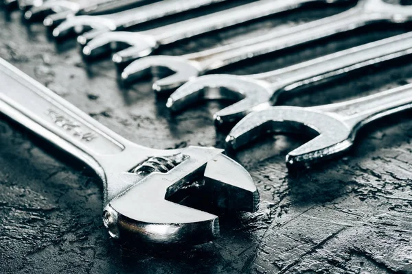 Close up view of metal wrenches on dark surface — Stock Photo