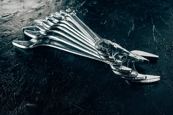 Close up view of arranged metal wrenches on dark surface — Stock Photo