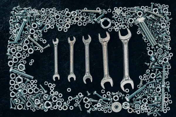 Flat lay with metal wrenches, screws and clinchers on dark surface — Stock Photo