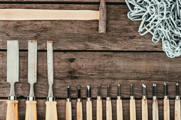 Deitado plano com corrente, martelo e cinzéis para madeira em mesa de madeira escura — Fotografia de Stock