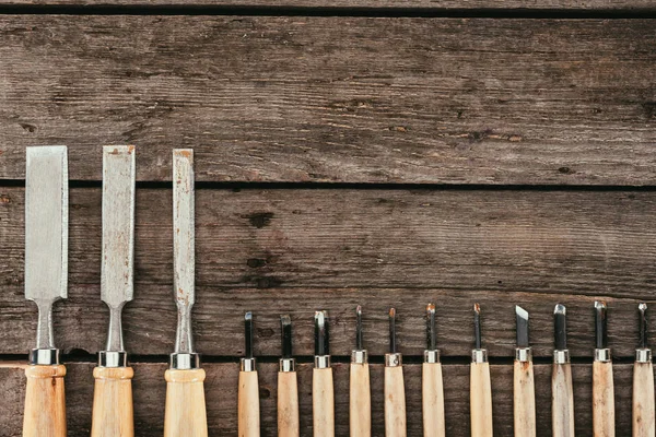 Leigos planos com cinzéis de madeira para madeira em mesa de madeira escura — Stock Photo