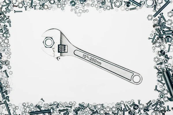 Top view of arranged various metal engineering details with wrench in middle isolated on white — Stock Photo