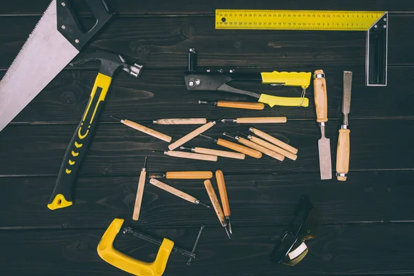 Top view of various carpentry tools on dark wooden surface — Stock Photo