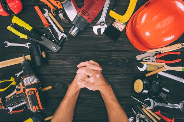 Partial view of hands in lock and carpentry equipment around on wooden surface — Stock Photo