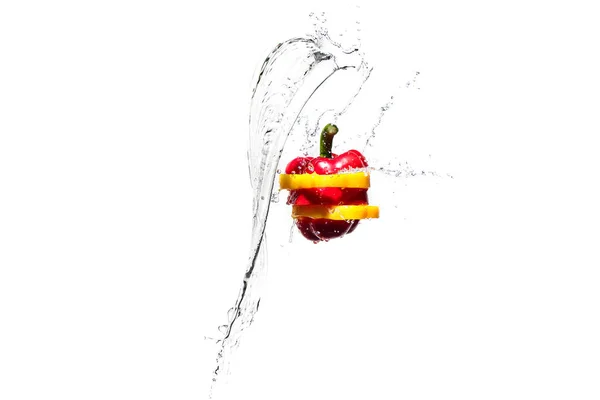 Червоний і жовтий шматочки болгарського перцю в бризках води ізольовані на білому — стокове фото