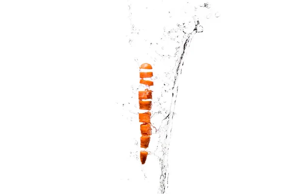 Carota fresca tagliata a fette in spruzzi d'acqua isolati su bianco — Foto stock