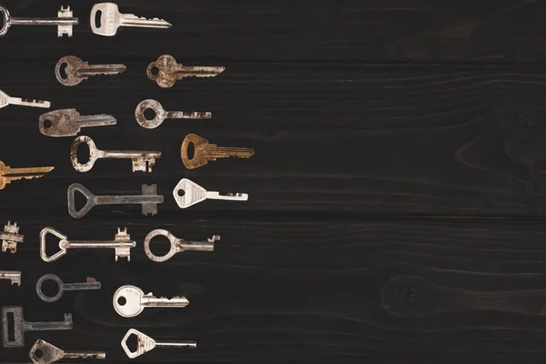 Vista superior de diferentes llaves vintage en la mesa negra - foto de stock