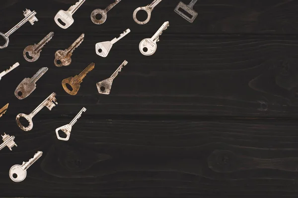 Вид зверху на різні старовинні ключі на чорному столі — стокове фото