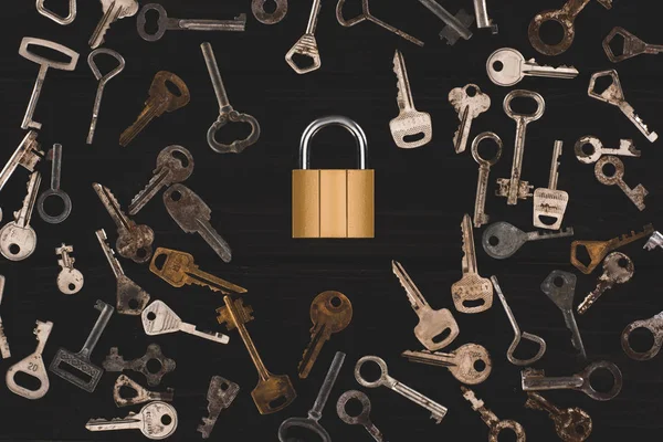 Top view of different metal keys with lock on black table — Stock Photo