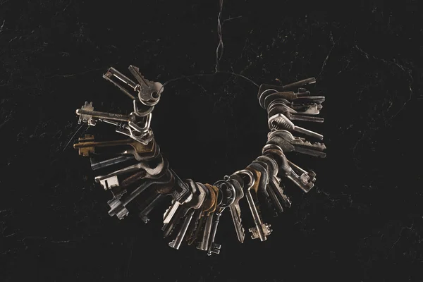 Ansicht von oben: Bündel verschiedener Schlüssel auf schwarzem Tisch — Stockfoto