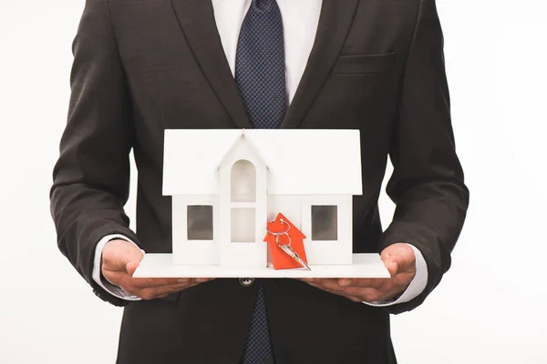 Imagen recortada de hombre sosteniendo maqueta de casa con llave aislada en blanco - foto de stock