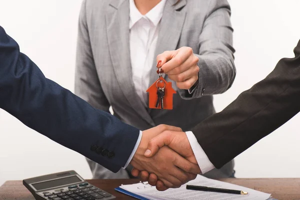 Imagen recortada de cliente y agente inmobiliario estrechando las manos, concepto de compra de bienes raíces aislado en blanco - foto de stock
