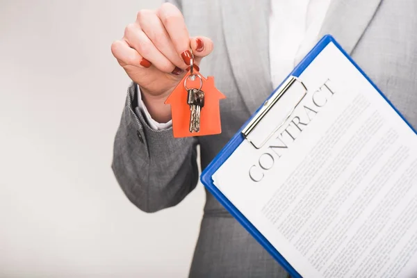 Immagine ritagliata di agente immobiliare in possesso di chiavi e contratto, concetto di acquisto di casa isolato su bianco — Foto stock