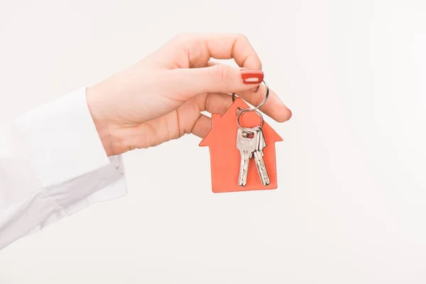 Imagen recortada de la mano femenina sosteniendo la llave de la casa aislada en blanco - foto de stock