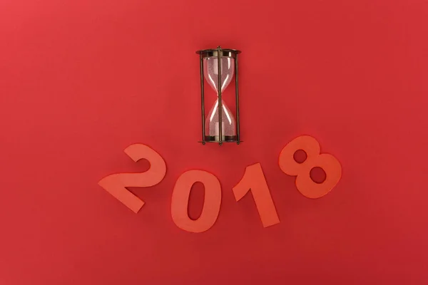 Vue du dessus de 2018 année signe et horloge de sable isolé sur rouge — Photo de stock