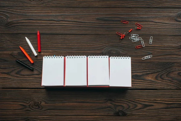 Draufsicht auf arrangierte Blanko-Kalender, Bleistifte, Clips und Anstecknadeln auf Holztischplatte — Stockfoto