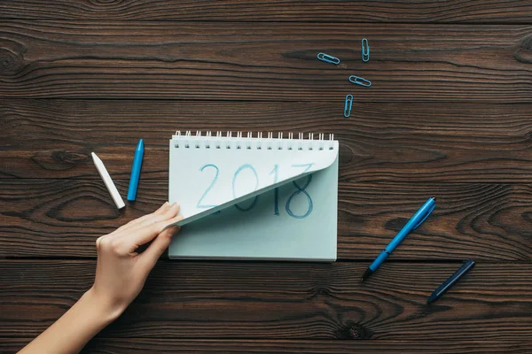 Foto recortada de mujer rasgando papel de cuaderno con el cartel del año 2018 en la mesa de madera — Stock Photo