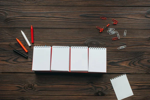 Vista dall'alto di calendario bianco organizzato, matite, clip e spilli su tavolo in legno — Foto stock