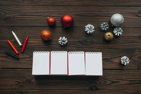 Tendido plano con calendario en blanco, lápices, conos de pino y juguetes de Navidad en la superficie de madera - foto de stock