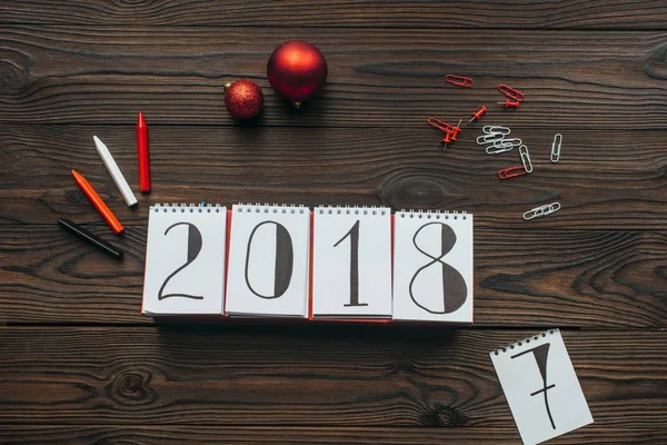 Flat lay with 2018 calendar, pencils and christmas toys on wooden surface — Stock Photo