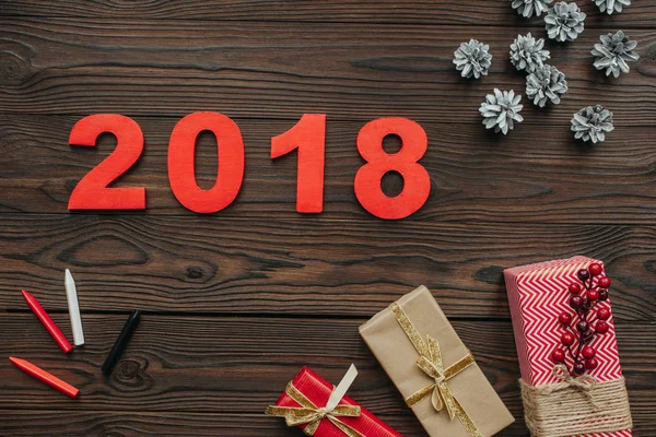 Flat lay with christmas gifts, pine cones and 2018 year sign on dark wooden tabletop — Stock Photo