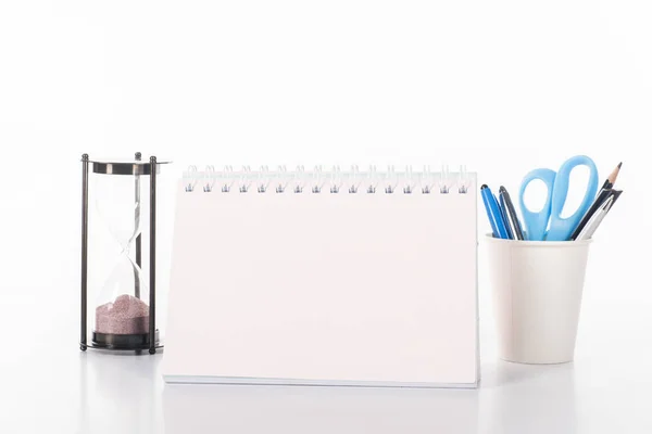 Vue rapprochée du calendrier vierge, de l'horloge en sable et des fournitures de bureau isolées sur blanc — Photo de stock