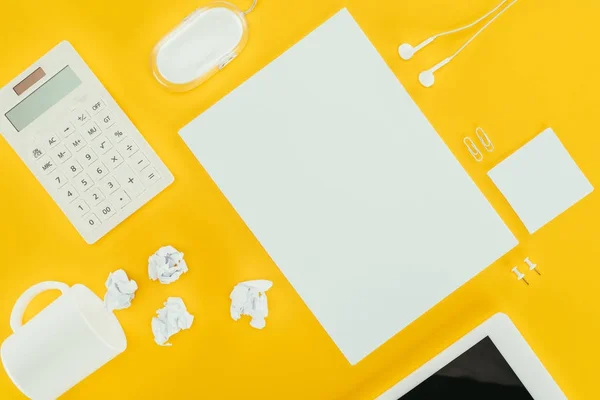 Top view of blank sheet of paper, crumpled papers, notes, calculator and computer mouse isolated on yellow — Stock Photo