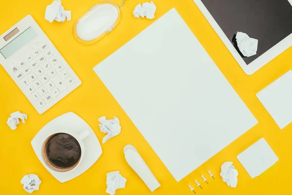 Top view of blank sheet of paper, crumpled papers, notes, calculator and digital tablet isolated on yellow — Stock Photo