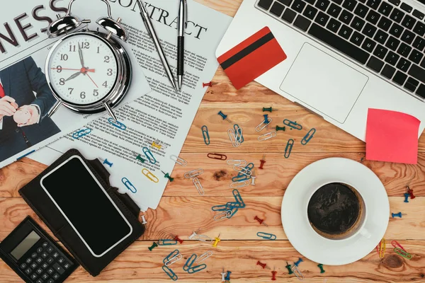 Vista superior do smartphone, contrato, jornal, cartão de crédito, laptop e material de escritório na mesa de madeira — Fotografia de Stock