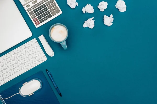 Top view of crumpled papers, calculator and digital devices on blue — Stock Photo