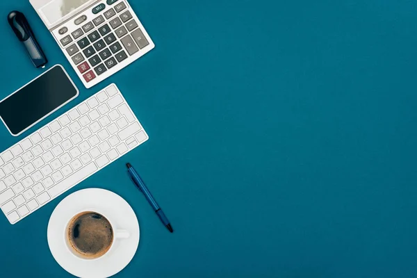 Vue du haut du smartphone, clavier et calculatrice sur fond bleu — Photo de stock