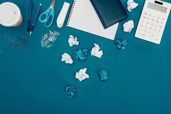 Top view of crumpled papers, calculator and office supplies on blue — Stock Photo