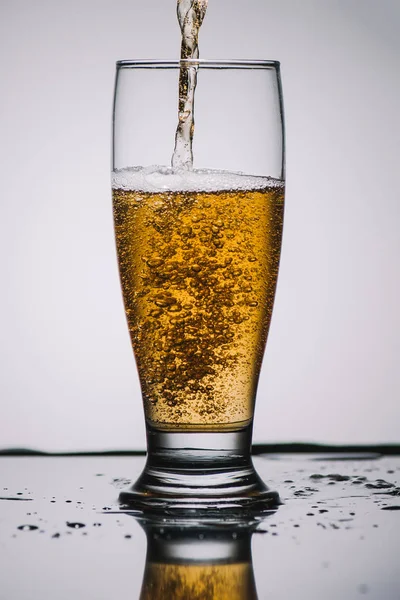 Pouring light beer into transparent glass — Stock Photo