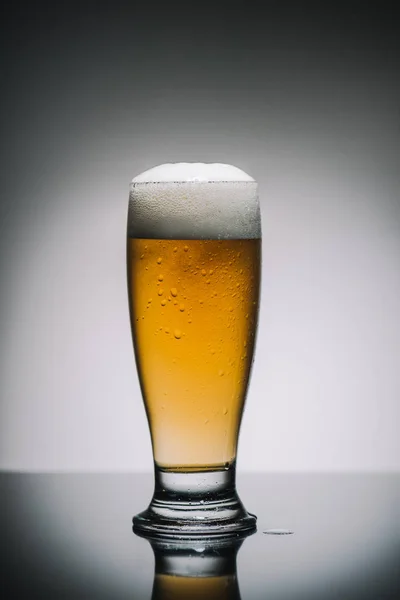 Plein verre de bière avec mousse sur la table — Photo de stock