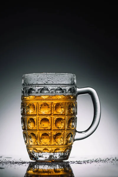 Glass with light cold beer with bubbles on gray reflecting surface — Stock Photo