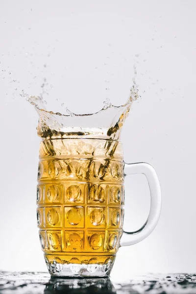 Splashes of cold light beer in transparent glass — Stock Photo