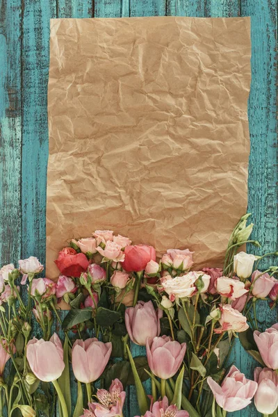 Vue de dessus de belles fleurs avec du papier artisanal sur fond de bois vert — Photo de stock